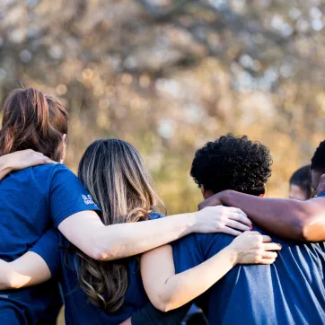group of young adults diverse interlocking arms from back